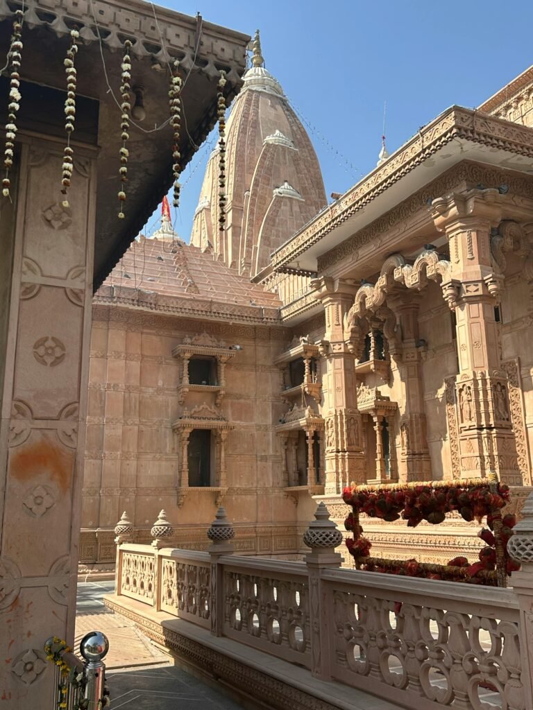 Beautiful sandstone carvings and ornate details of a Hindu temple courtyard under clear blue sky.
